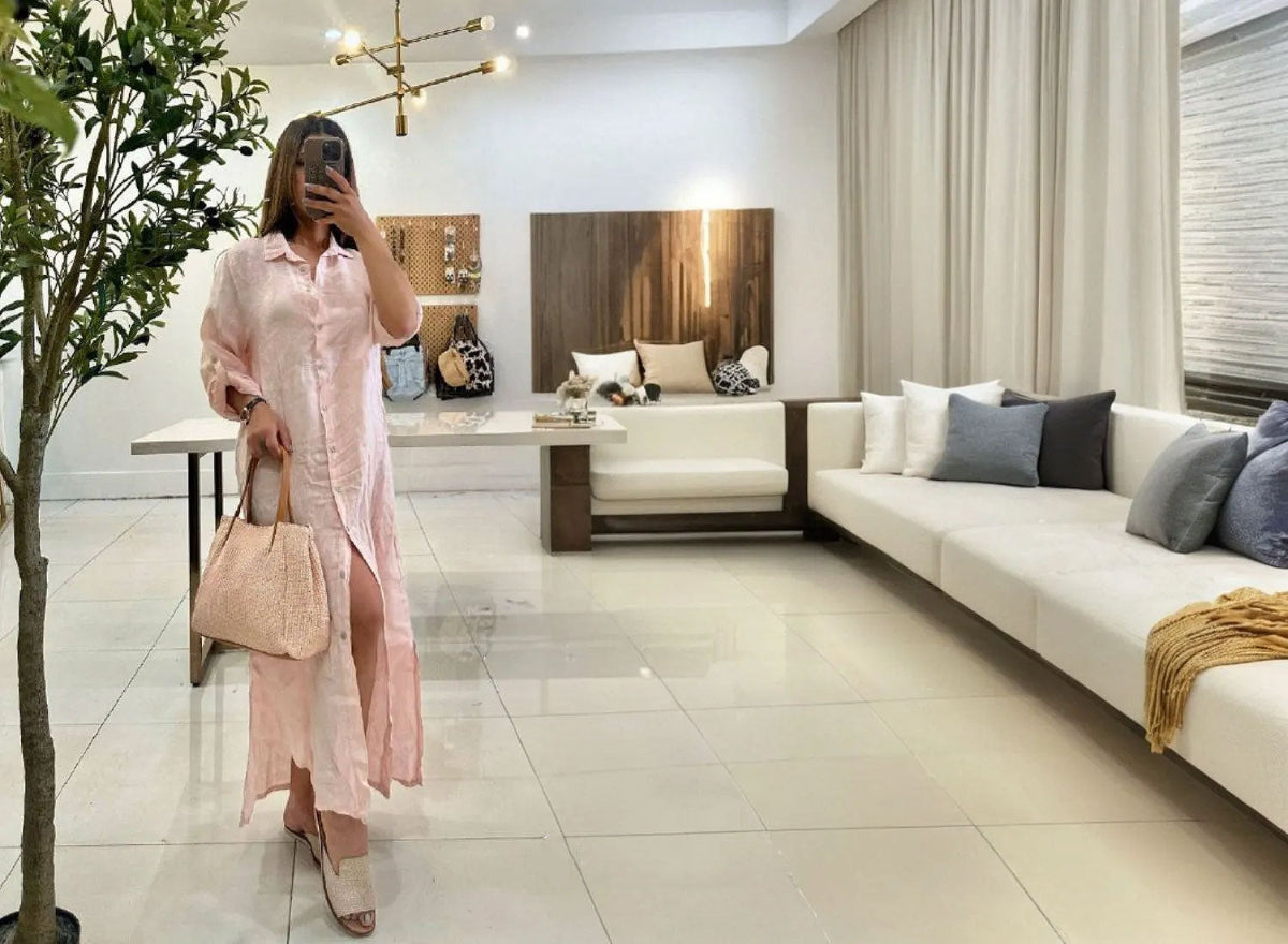 Woman taking a mirror selfie in a modern living room with a white sofa and decorative pillows.